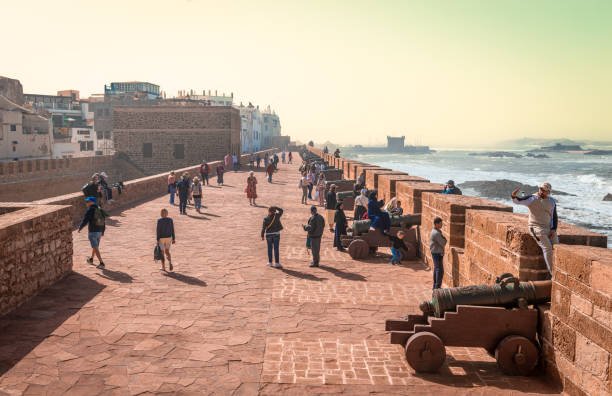 Essaouira, Morocco - February 19 2024: People walk at the ramparts of the old city that overlook the Atlantic Ocean.